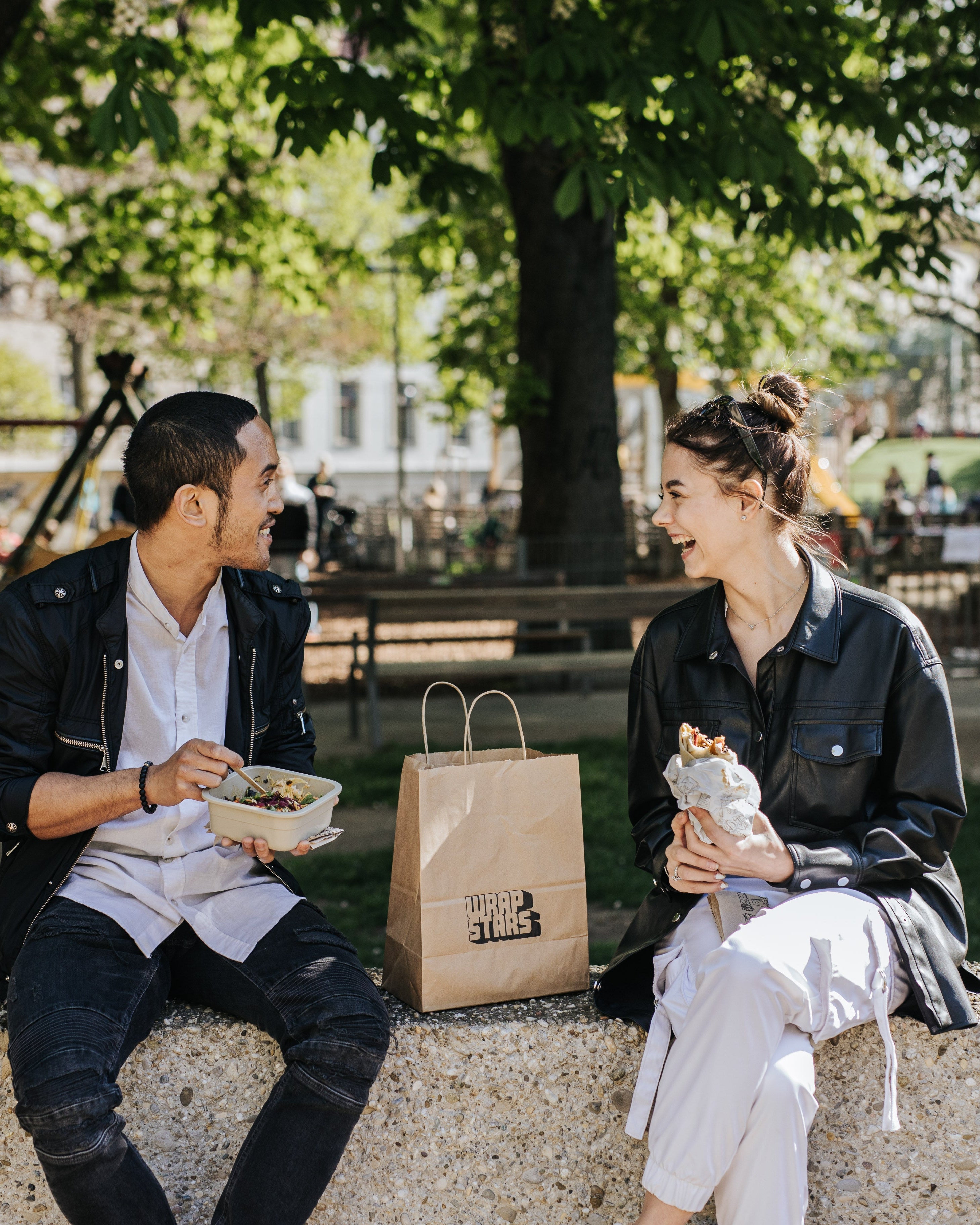 Ein junger Mann und eine junge Frau genießen gemeinsam ein Lunchpakete mit Wraps von Wrapstars Catering