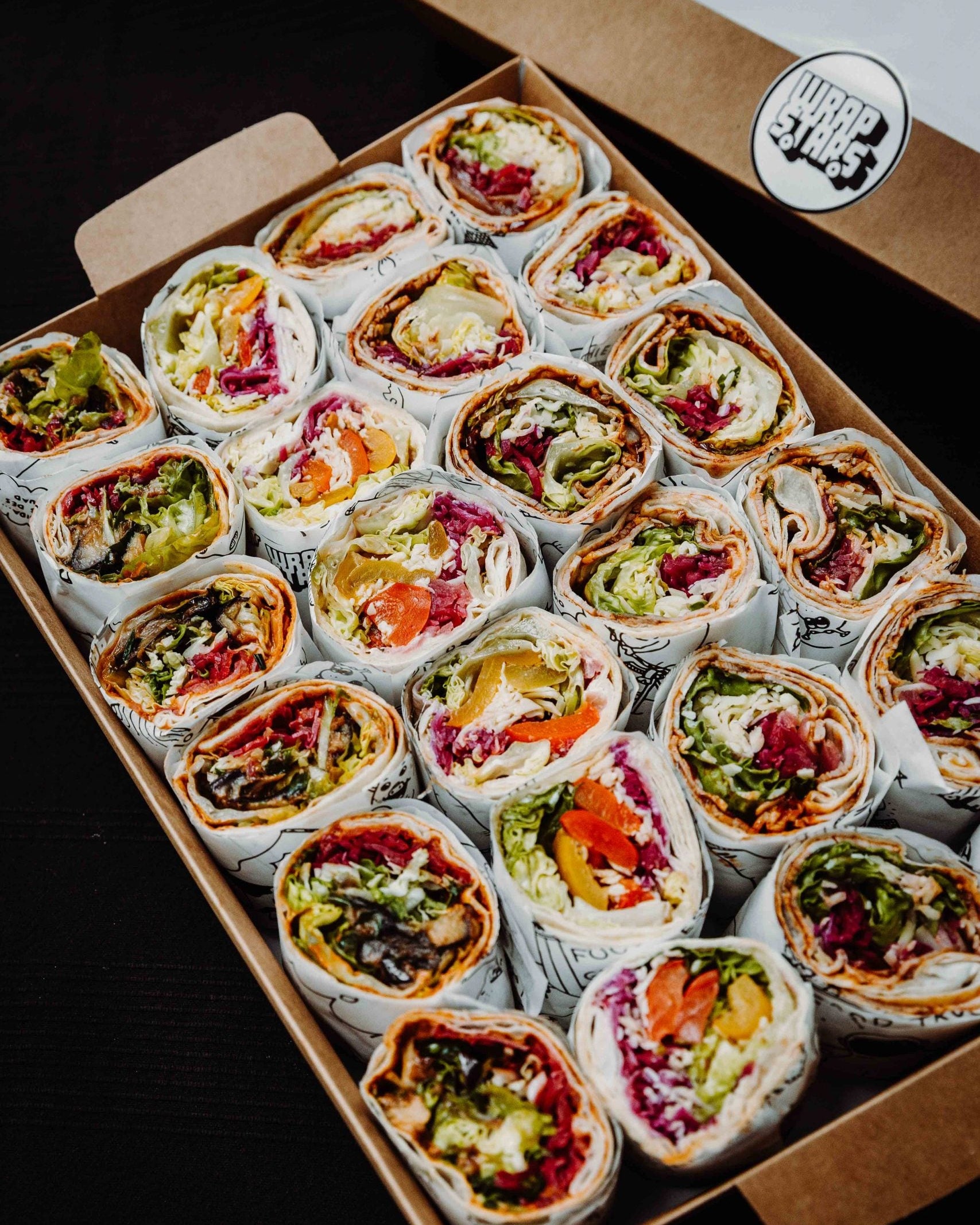 Eine Nahaufnahme von schön sortierten Wraps von Wrapstars mit frischem Salat in einer Wrapbox für ein Catering