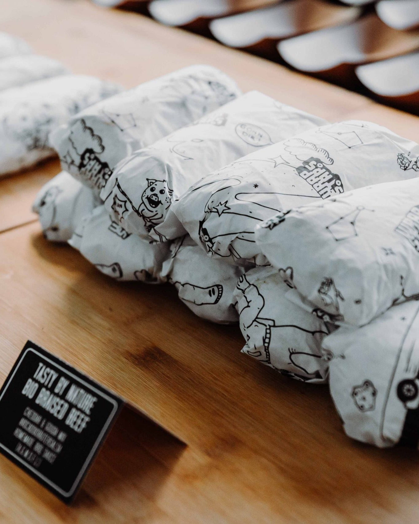 Burritos in gebrandetem Wickelpapier von Wrapstars Catering verpackt. Schön sortiert auf einem Tisch mit Beschriftung davor.