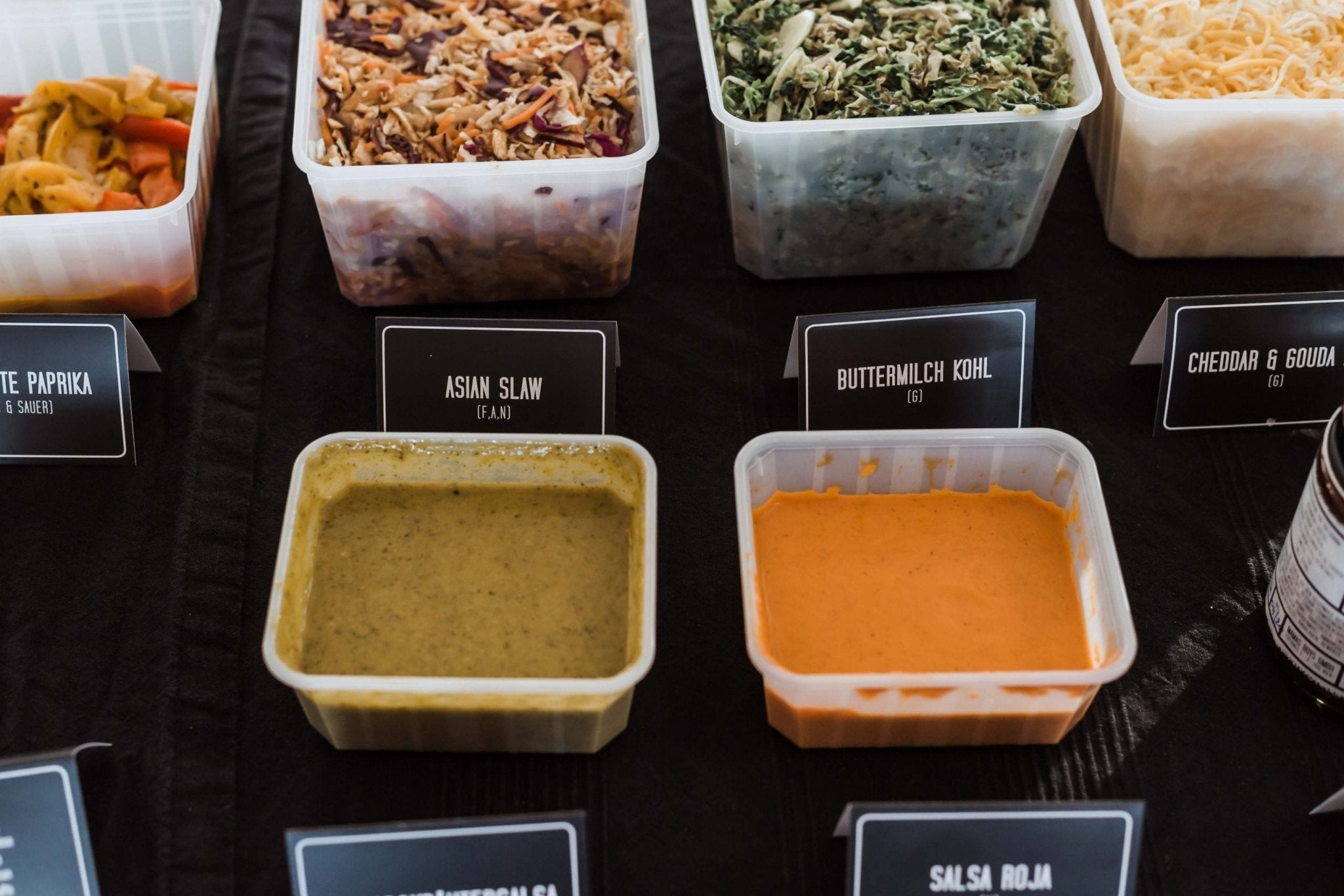 Nahaufnahme der Toppings einer Taco bar mit Salsa Roja, Erbsensalsa und Soyslaw uvm.