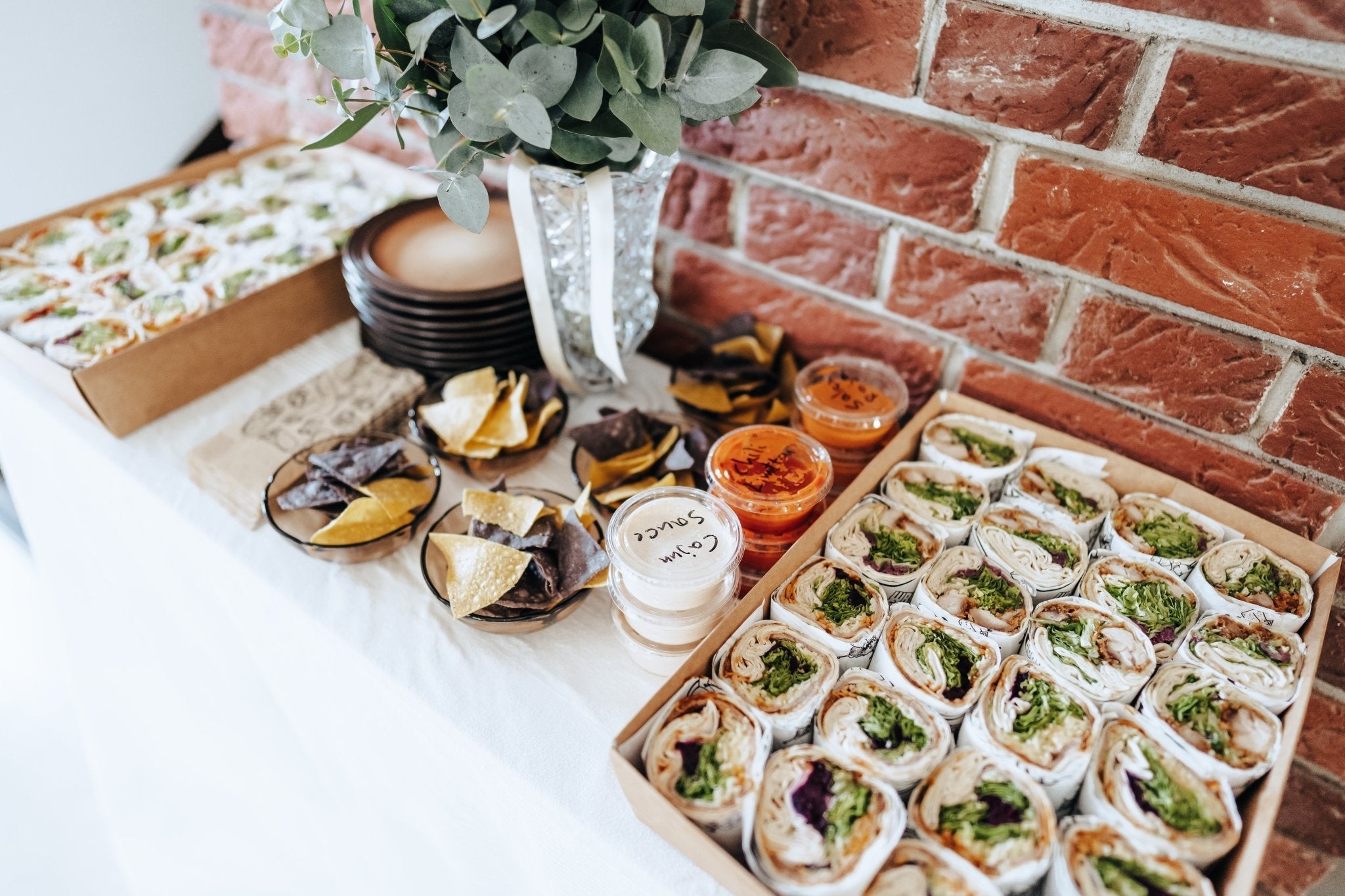 Wrapboxen mit frischen Wraps, Tortilla-Chips und verschiedenen Dips – auf einem Tisch schön für ein Catering präsentiert.