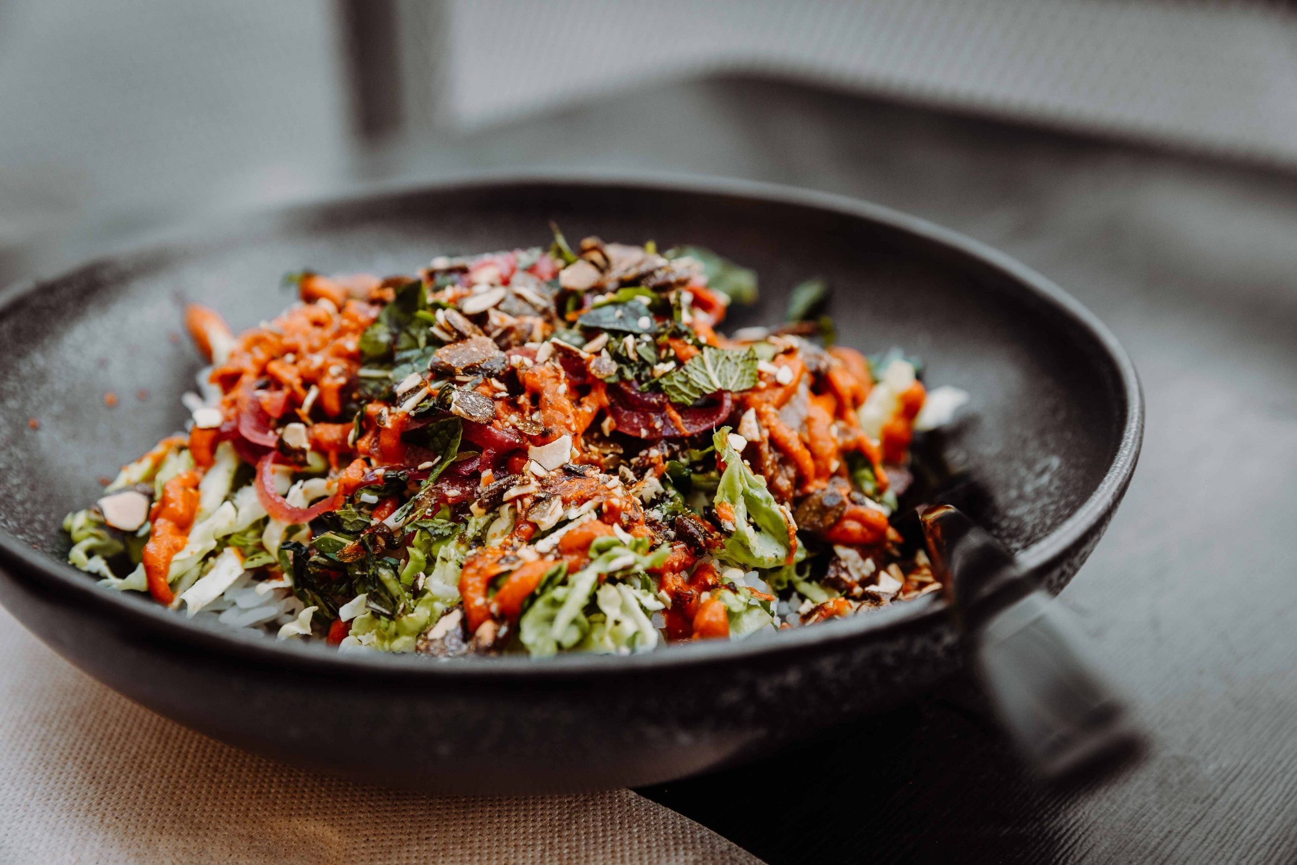 Nahaufnahme einer Burrito Bowl mit Reis, Salsa und einer Sauce und pickled Veggies und Toppings von Wrapstars Catering