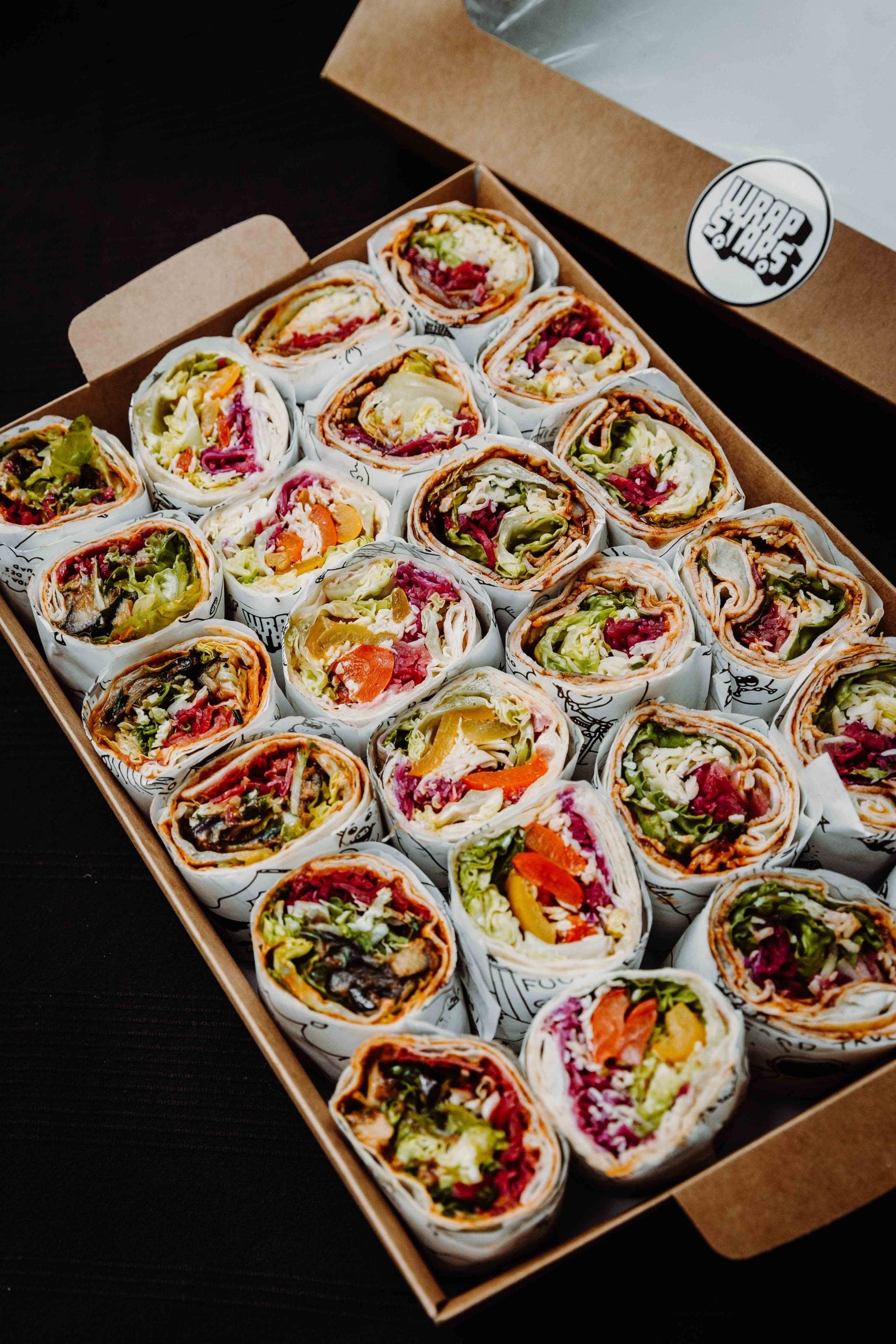 Eine Nahaufnahme von schön sortierten Wraps von Wrapstars mit frischem Salat in einer Wrapbox für ein Catering