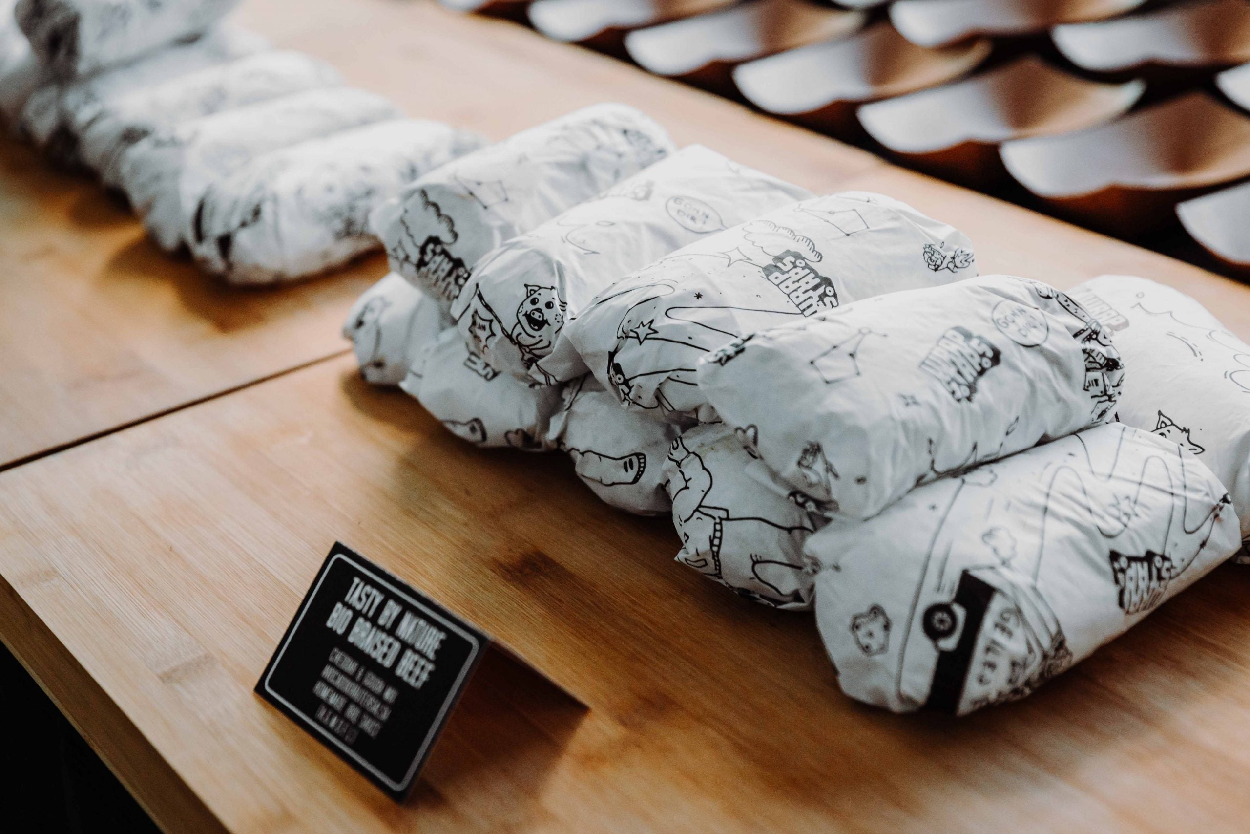 Burritos in gebrandetem Wickelpapier von Wrapstars Catering verpackt. Schön sortiert auf einem Tisch mit Beschriftung davor.