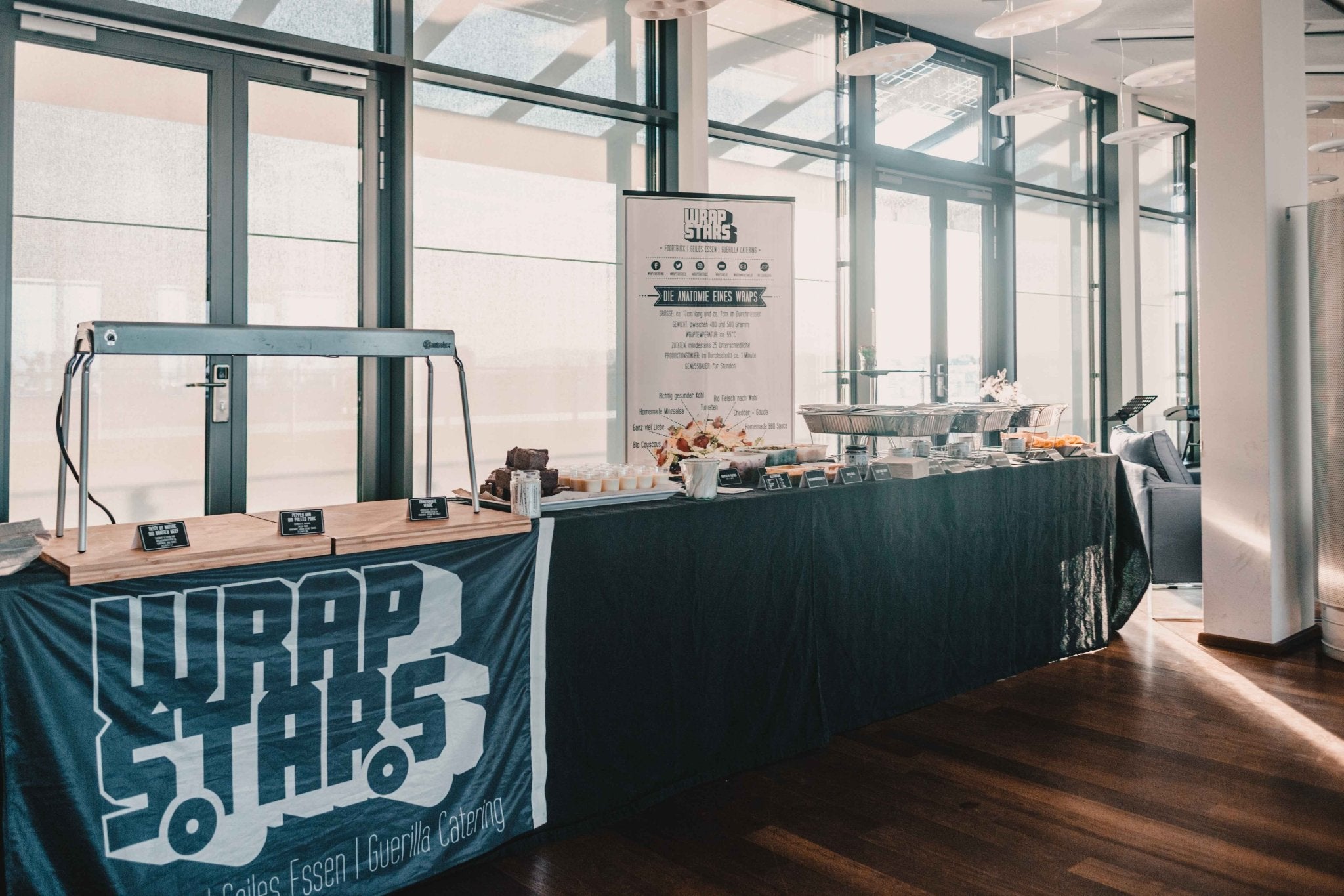 Aufbau von einem Catering Buffet von Wrapstars mit schwarzen Tischdecken und einer Taco Bar mit frischen Zutaten.