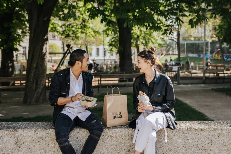 Two friends enjoying wraps in a park
