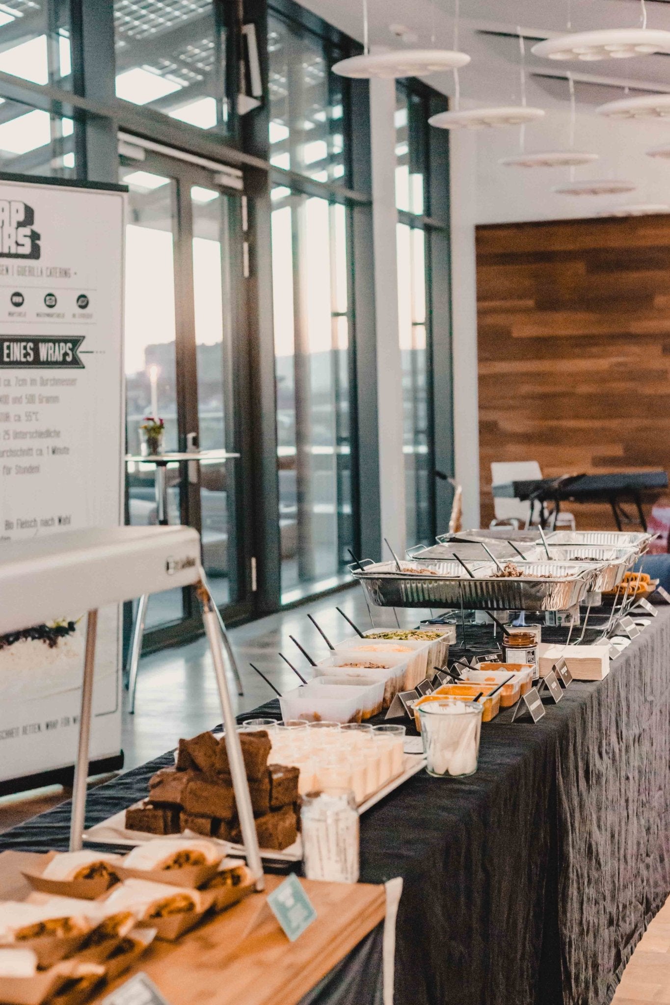 Aufbau von einem Catering Buffet von Wrapstars mit schwarzen Tischdecken und einer Taco Bar mit frischen Zutaten.