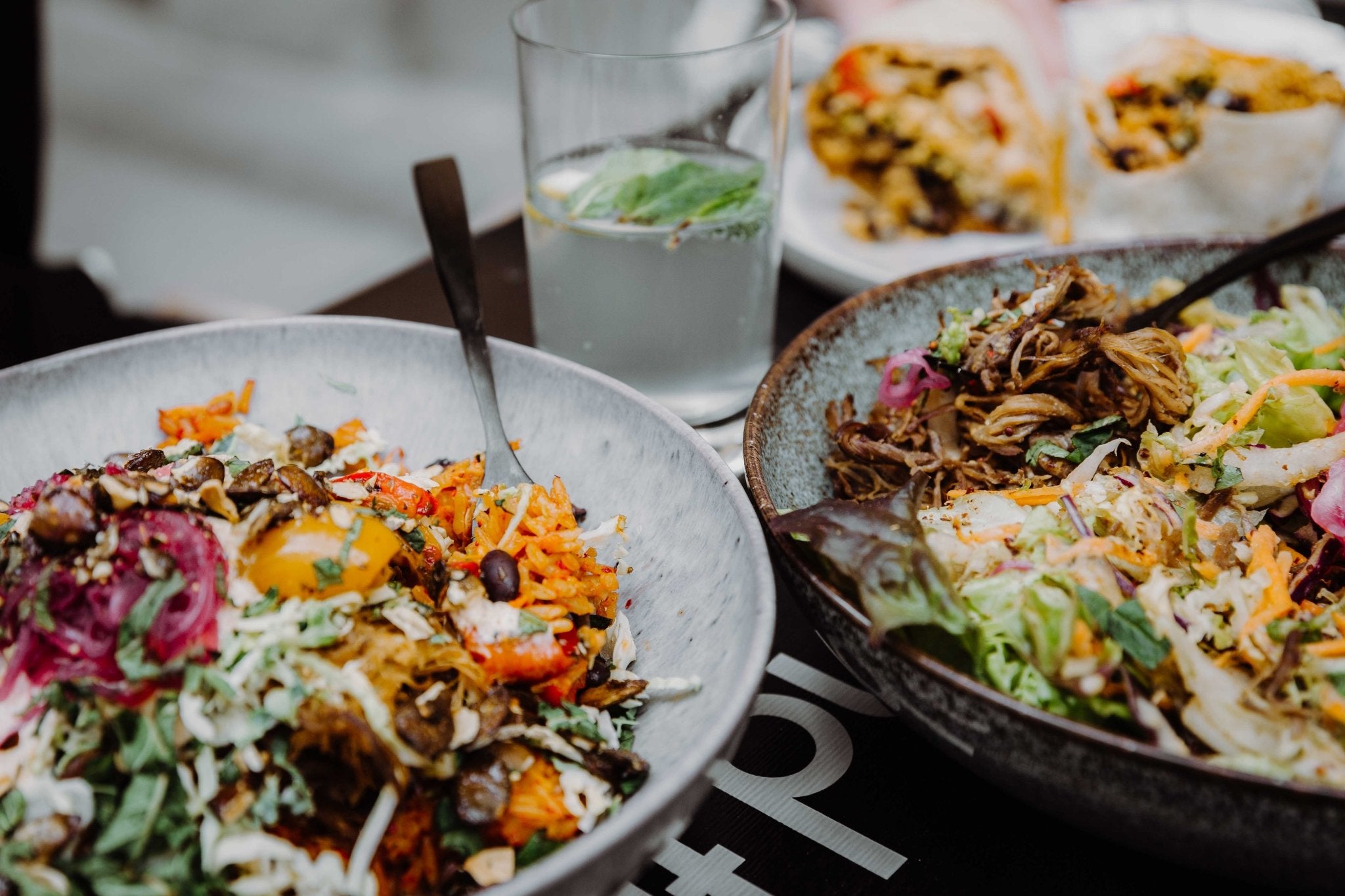 Nahaufnahme von zwei Burrito Bowls mit Reis, Salsa und einer Sauce und pickled Veggies und Toppings