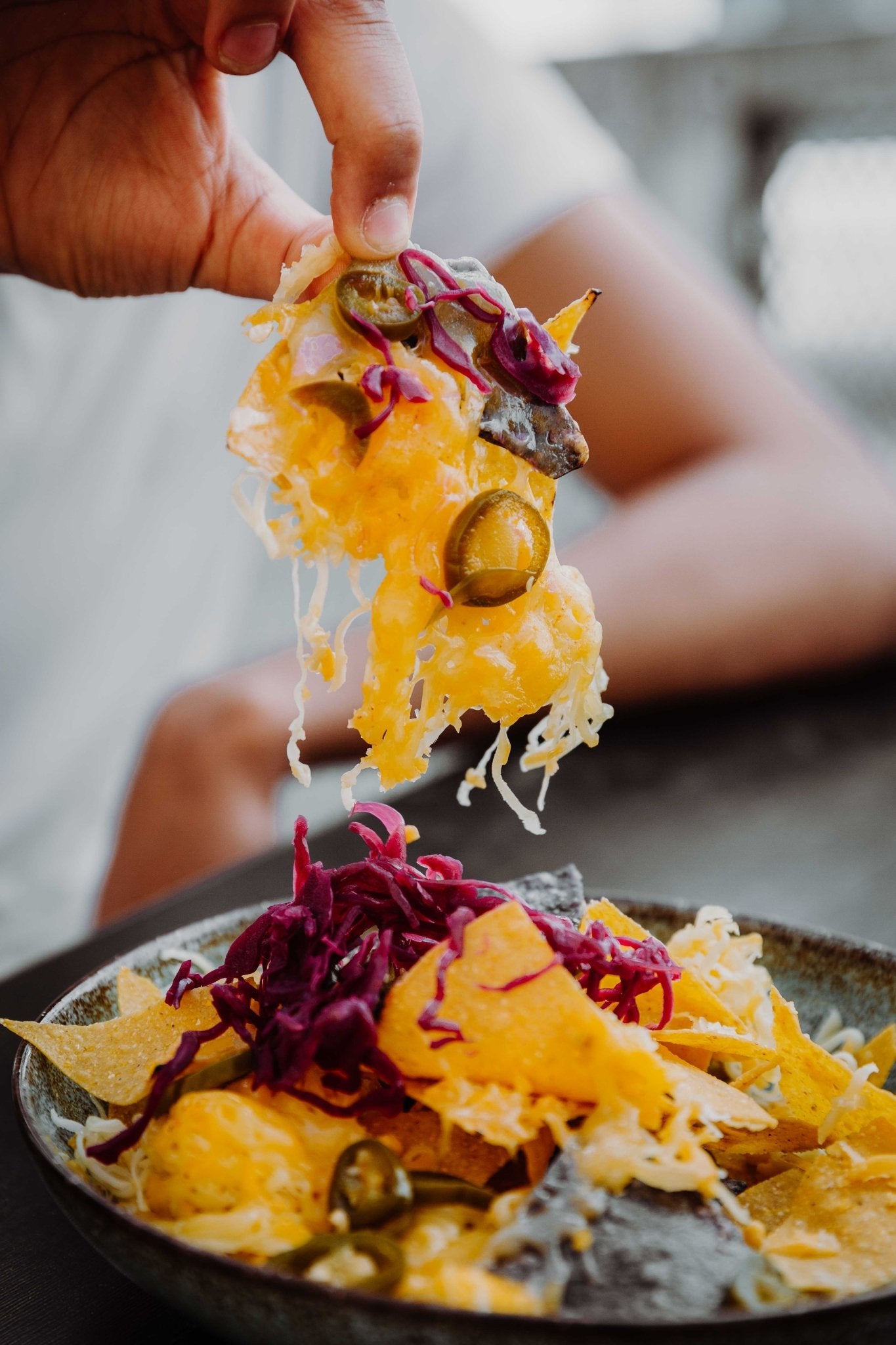 Nahaufnahme von einer Hand die Loaded Nachos mit viel geschmolzenem  Käse bei Wrapstars isst.
