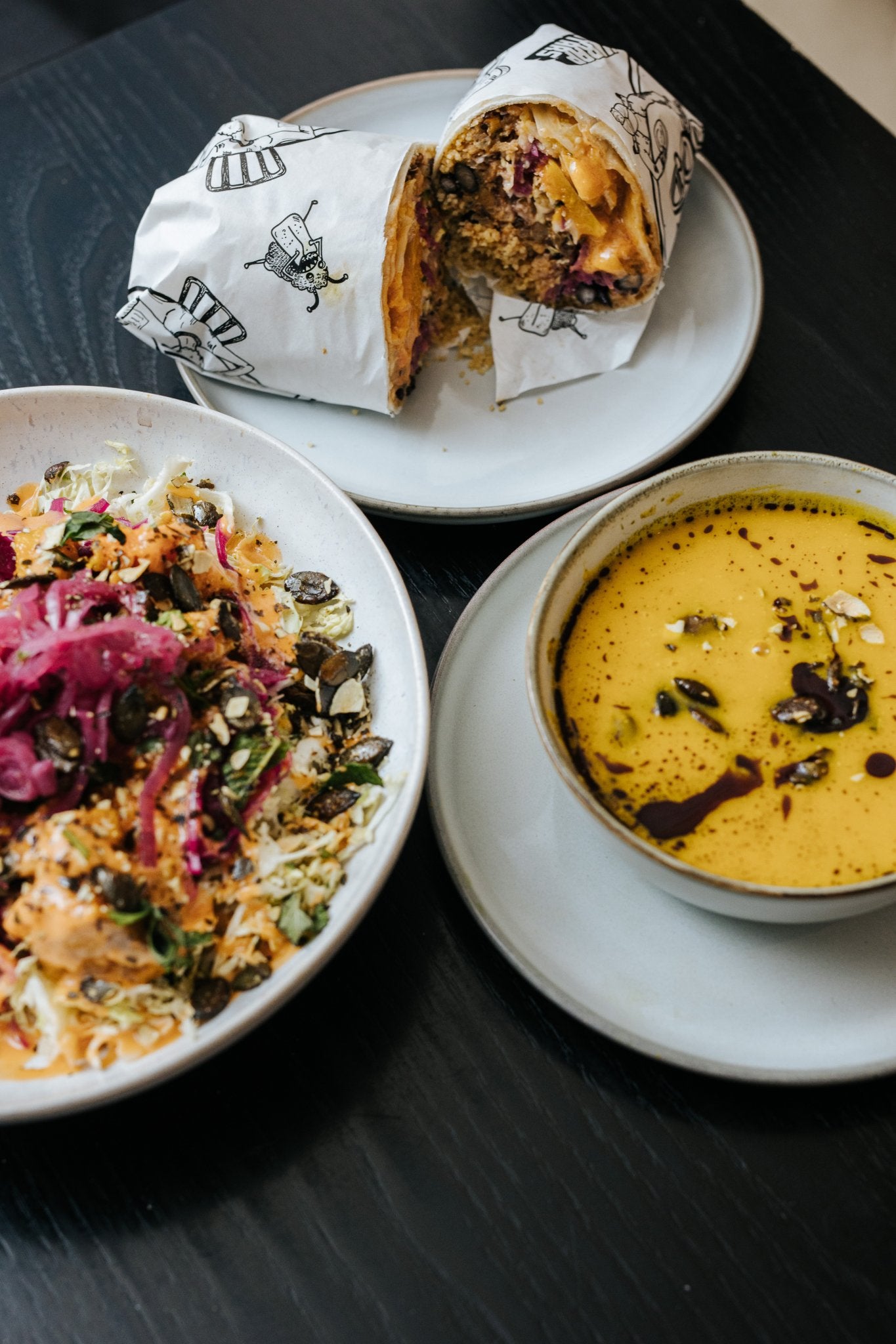Burrito Bowl, Suppe und ein aufgeschnittener Burrito auf Tellern serviert.
