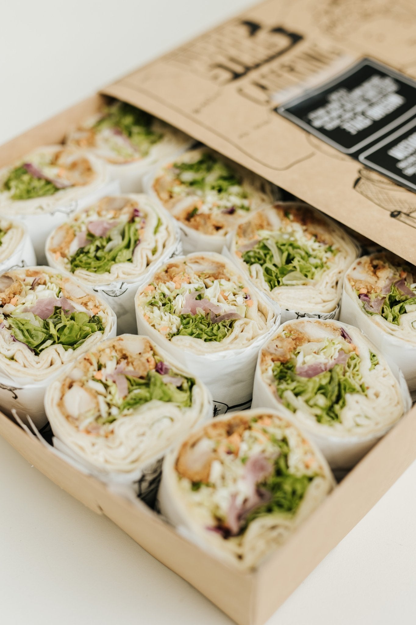 Eine Nahaufnahme von schön sortierten Wraps von Wrapstars mit frischem Salat in einer Wrapbox für ein Catering