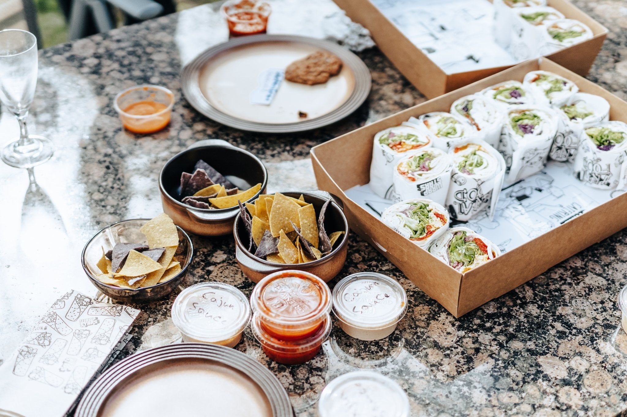 Wrapboxen mit frischen Wraps, hausgemachten Tortilla-Chips und verschiedenen Dips – schön angerichtet auf einem dekorierten Tisch für ein Team Lunch.

Copyright: www.loview.si